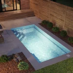 Piscine creusée en fibre de verre Mova, modèle 10x20, finition Diamant couleur Mova, ambiance soirée éclairée